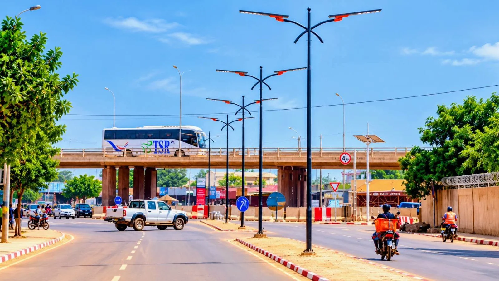 Double-arm all-in-one solar street lights along a road and overpass in a West African city by day