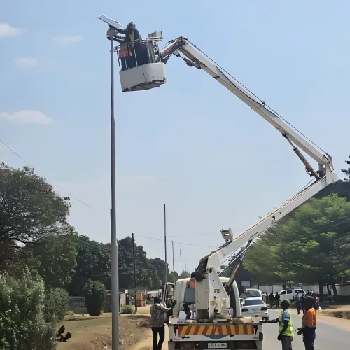 Two workers in a bucket truck are elevated to repair a street light pole.