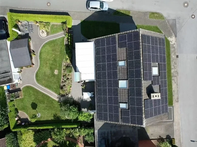 Aerial view of a residential house with a full solar panel rooftop installation